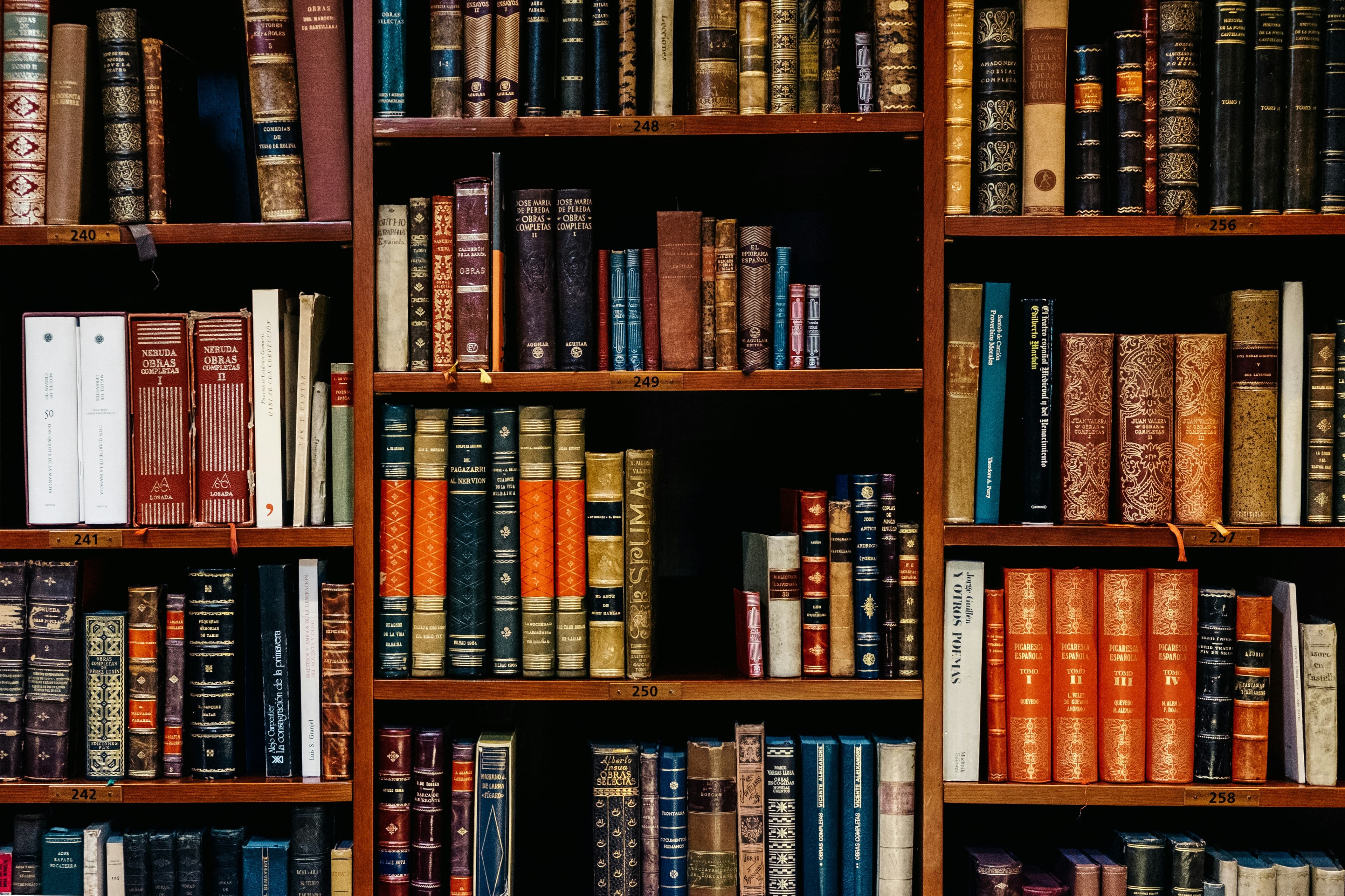 Estanterías de madera llenas de libros encuadernados.